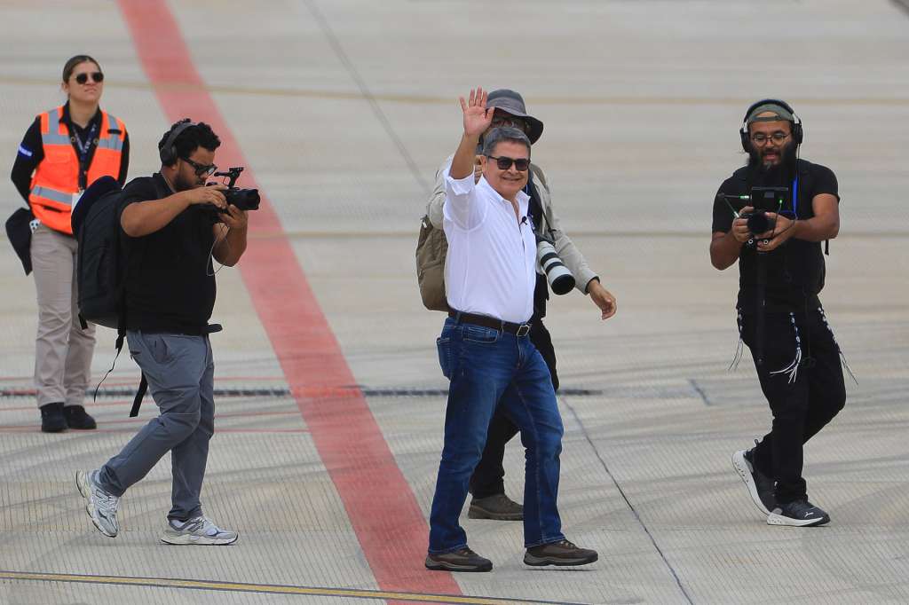 AME3061. COMAYAGUA (HONDURAS), 26/07/2026.- El expresidente hondureño Juan Orlando Hernández (c) (2014-2022) saluda este domingo, a su llegada al Aeropuerto Internacional de Palmerola en Comayagua (Honduras). Hernández regresó a Honduras para enfrentar un proceso judicial por fraude y lavado de activos, casi ocho meses después de recibir un indulto total del presidente estadounidense, Donald Trump, que anuló su condena de 45 años por narcotráfico. EFE/ Gustavo Amador