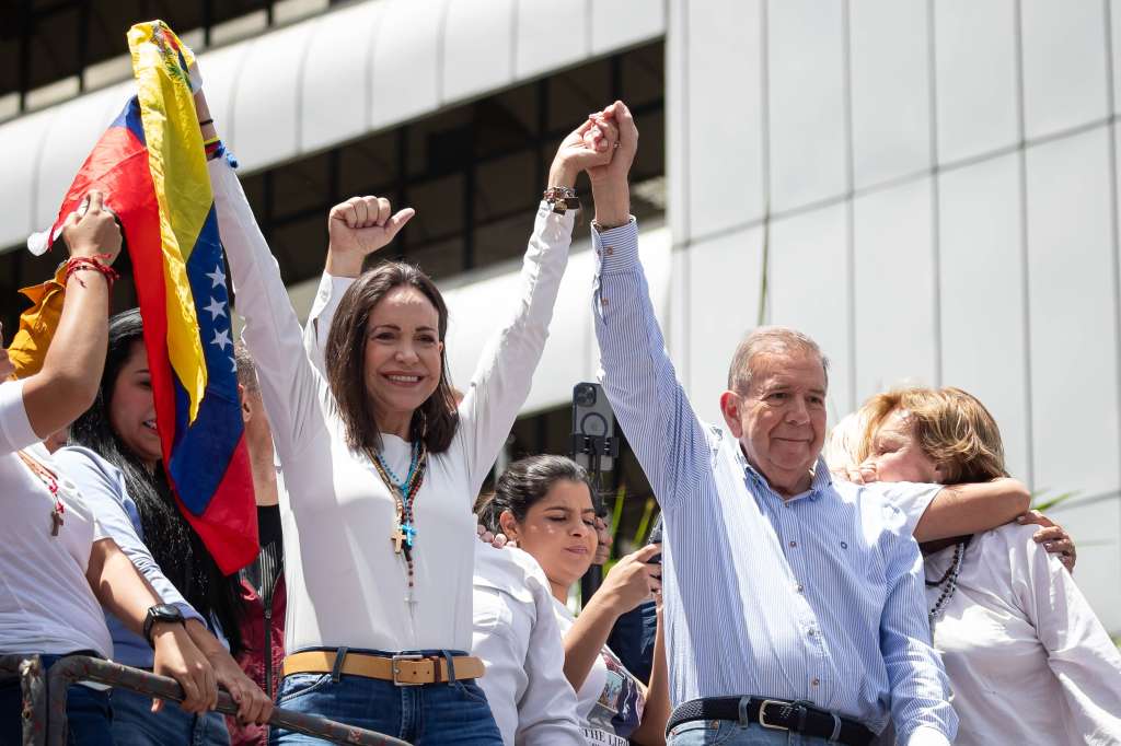 AME6560. CARACAS (VENEZUELA), 30/07/2024.- La líder opositora venezolana María Corina Machado (i) y el candidato a la presidencia de Venezuela Edmundo González Urrutia saludan en una manifestación de apoyo este martes, en Caracas (Venezuela). Miles de venezolanos se han concentrado este martes en Caracas, en un acto convocado por la oposición mayoritaria, para rechazar por segundo día consecutivo lo que consideran es un fraude en los resultados oficiales del Consejo Nacional Electoral (CNE), que en la víspera proclamó a Nicolás Maduro como presidente reelecto con el 51,2 % de los votos. EFE/ Ronald Peña R.