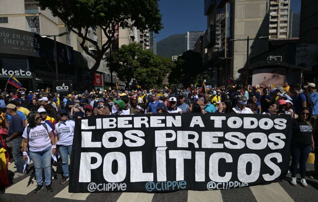 (FILES) Demonstrators hold a banner demanding for the release of all political prisoners during a protest called by the opposition on the eve of the presidential inauguration, in Caracas on January 9, 2025.