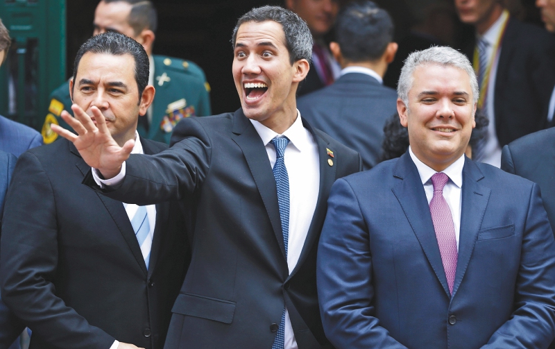 Venezuela's self-proclaimed interim president Juan Guaido waves alongside, from left, Guatemala's President Jimmy Morales, Colombia's President Ivan Duque and Panama's President Juan Carlos Varela as they gather for a group photo after attending an emergency Lima Group meeting concerning Venezuela, in Bogota, Colombia, Monday, Feb. 25, 2019. As it struggles to find new ways to boost Guaido after an effort to deliver humanitarian aid to the economically devastated nation faltered amid strong resistance from security forces who remain loyal to Venezuela's President Nicolas Maduro, the Trump administration announced new sanctions on Maduro's allies. (AP Photo/Martin Mejia)