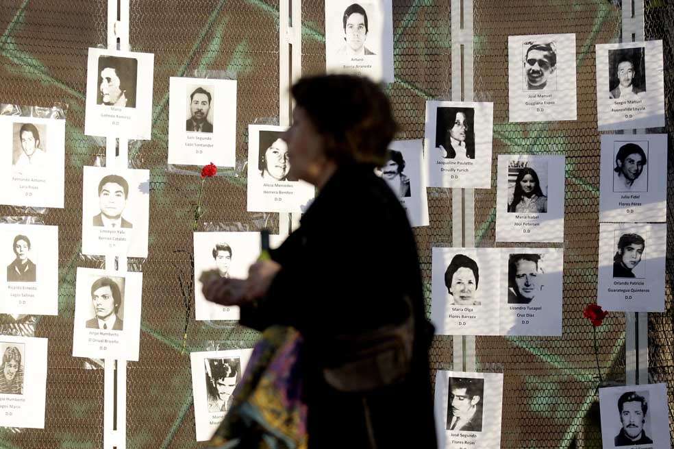 Una mujer camina frente a varias imágenes de víctimas de la dictadura chilena, durante el 41º aniversario del golpe militar que lideró el general Augusto Pinochet el 11 de septiembre de 1973. / EFE