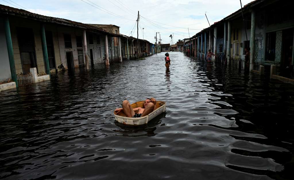 TOPSHOT - A man rides a handmade raft through a flooded street in Batabano, Mayabeque province, Cuba, on September 26, 2024, following the passage of Hurricane Helene.