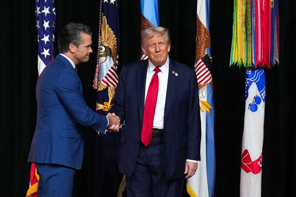 El secretario de Guerra de Estados Unidos, Pete Hegseth, estrecha la mano del presidente Donald Trump mientras este sube al escenario para dirigirse a los altos oficiales militares reunidos en Quantico, Virginia.
