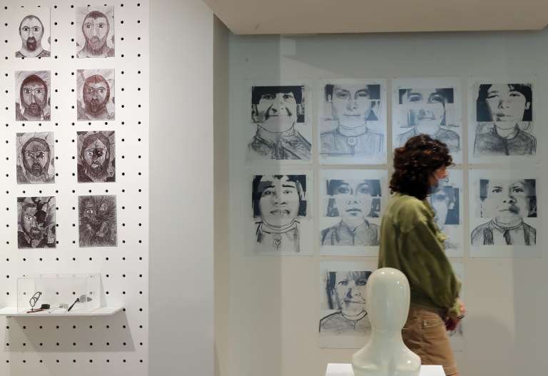 MEX8522. CIUDAD DE MÉXICO (MÉXICO), 13/07/2022.- Una mujer observa la obra "Lecciones para un identikit alterno" (s/f) de la muestra "Desde adentro", exhibida en el Museo del Objeto en Ciudad de México (México). La muestra “Desde Adentro” recoge 52 obras de 54 pacientes psiquiátricos del sistema penitenciario de la Ciudad de México y abre el panorama del mundo artístico a la vez que muestra el valor de esta disciplina. EFE/ Alex Cruz