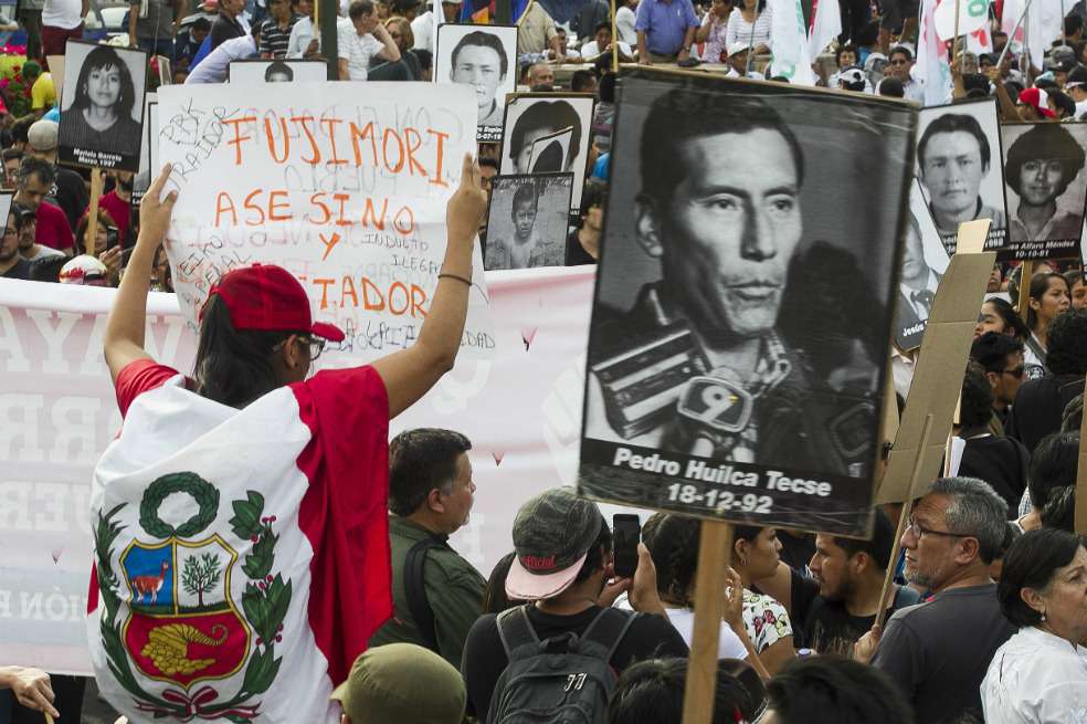 Manifestantes participan con banderas y pancartas durante una marcha contra el indulto otorgado al expresidente Alberto Fujimori. / EFE