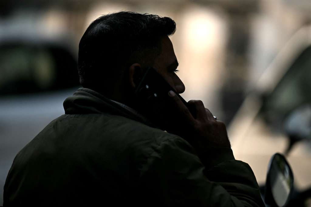 In this photograph taken on December 9, 2024, a field detective speaks on his mobile phone before leaving for an assignment, in New Delhi.