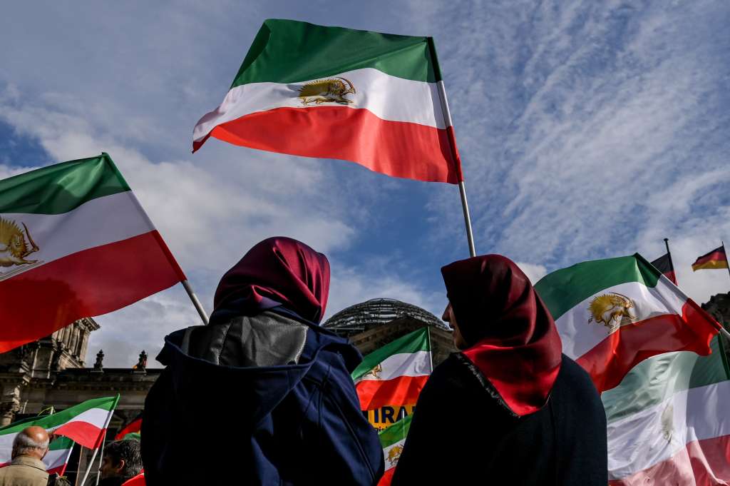 Berlin (Germany), 28/09/2022.- Participant hold Iranian flags during a rally in front of the Reichstag building in Berlin, Germany, 28 September 2022. Iran has been facing many anti-government protests following the death of Mahsa Amini, a 22-year-old Iranian woman, who was arrested in Tehran on 13 September by the morality police, a unit responsible for enforcing Iran's strict dress code for women and died while in their custody. (Protestas, Alemania, Teherán) EFE/EPA/FILIP SINGER