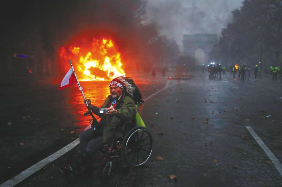 Un manifestante se toma una selfie con las protestas y el Arco del Triunfo de fondo. / EFE