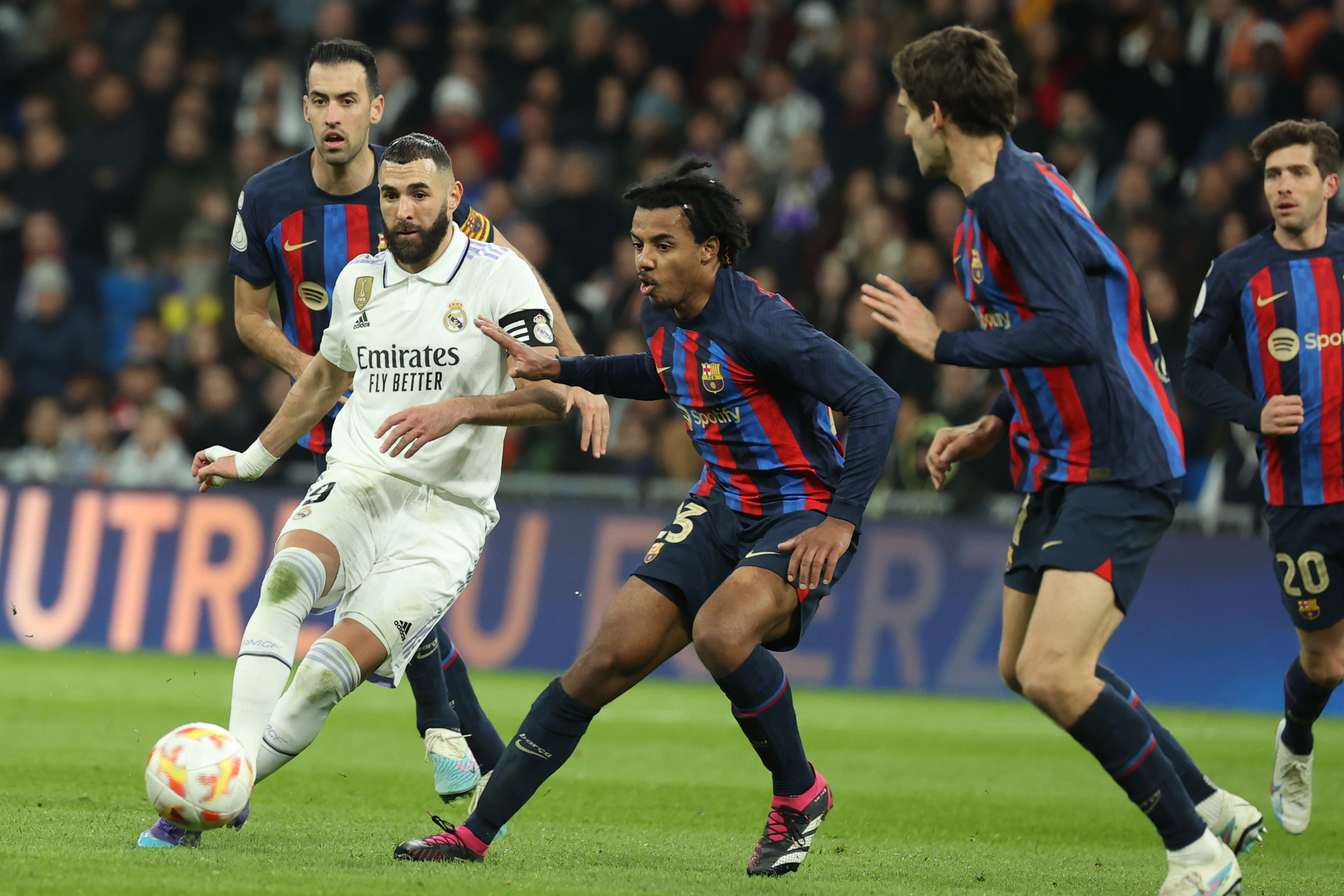 MADRID, 02/03/2023.- El delantero del Real Madrid Karim Benzemá (2-i) juega un balón ante Jules Koundé (c), del Barcelona, durante el partido de ida de las semifinales de la Copa del Rey que Real Madrid y FC Barcelona disputan este jueves en el estadio Santiago Bernabéu. EFE/Kiko Huesca