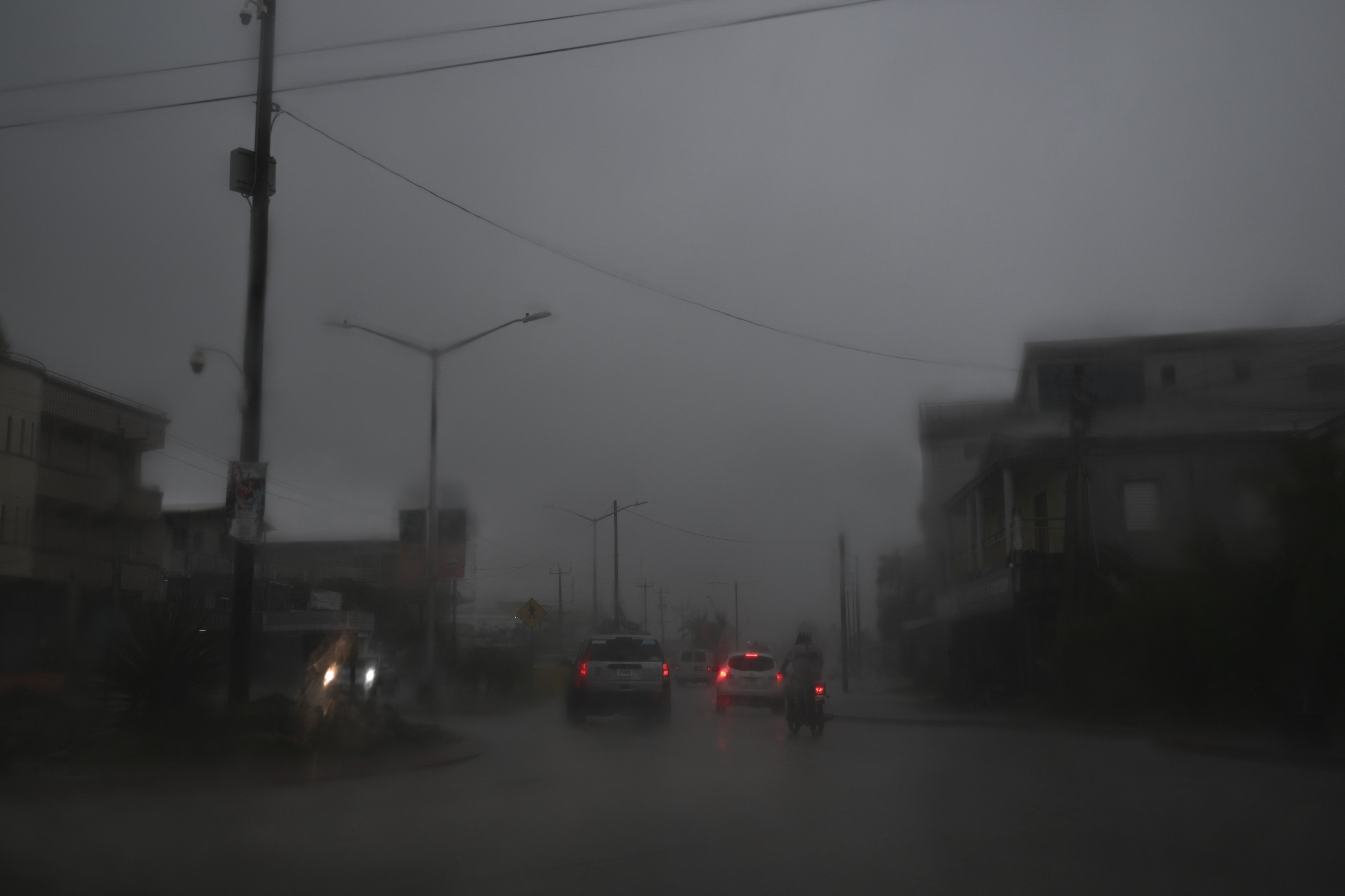 Vehículos avanzan por una calle inundada debido a las fuertes lluvias antes de la llegada del huracán Lisa a la ciudad de Belice el 2 de noviembre de 2022.