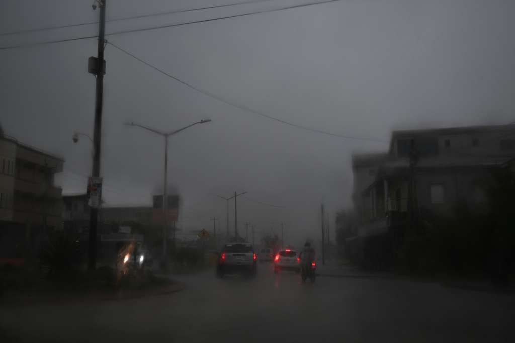 Vehículos avanzan por una calle inundada debido a las fuertes lluvias antes de la llegada del huracán Lisa a la ciudad de Belice el 2 de noviembre de 2022.