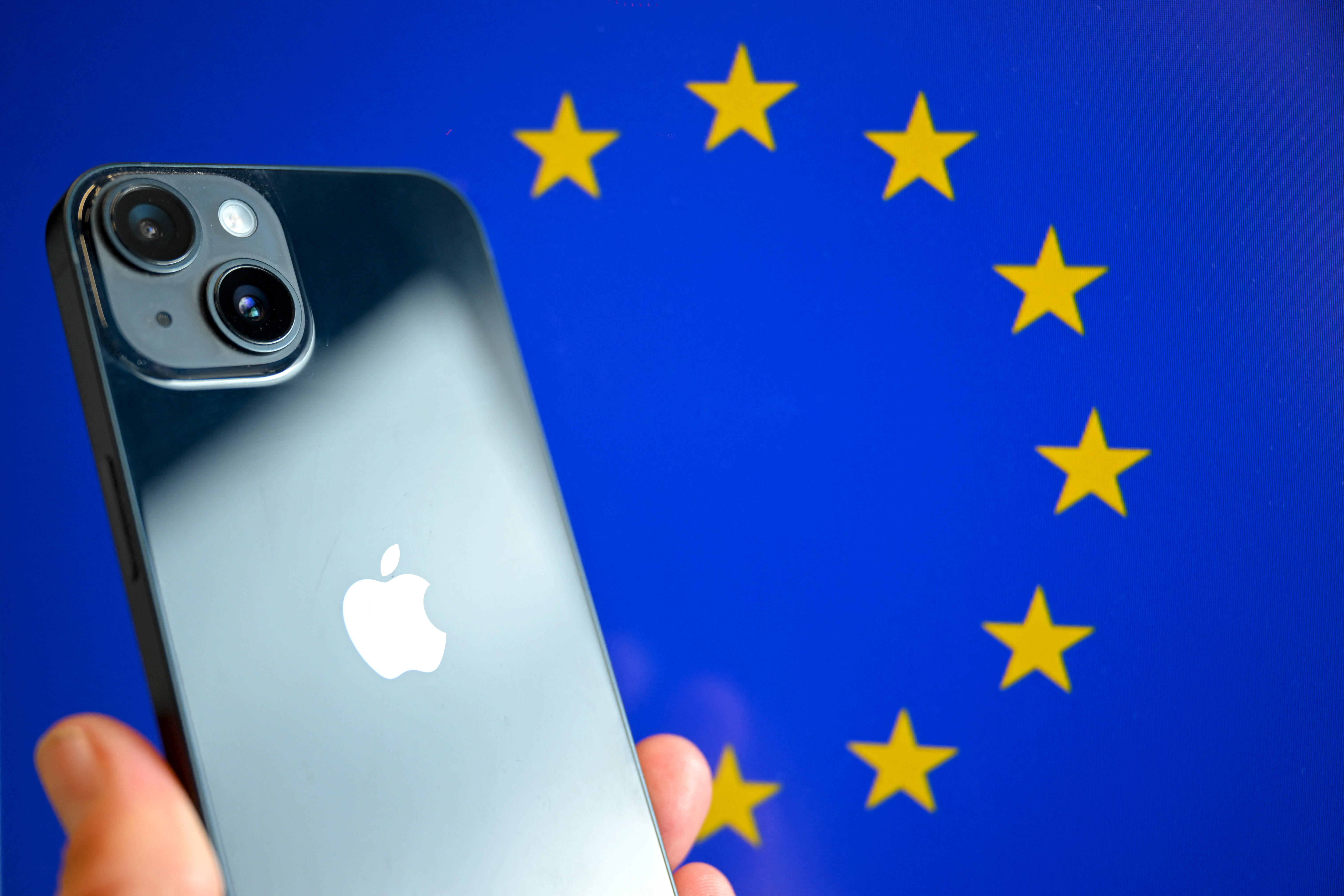 This photograph shows a hand-held smartphone with the Apple company logo and the European Union logo in the background, in Brussels on September 9, 2024.