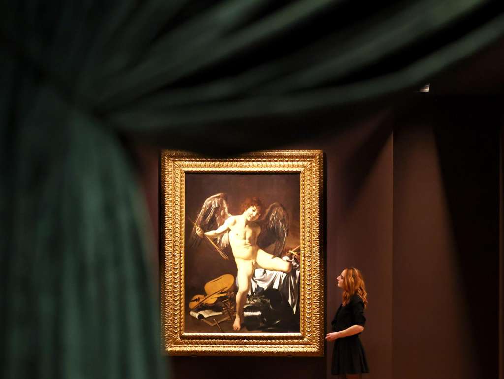 LONDON (United Kingdom), 23/11/2025.- A gallery worker poses with the work 'Victorious Cupid'(1601-02) by Italian artist Michelangelo Merisi da Caravaggio at the Wallace Collection in London, Britain, 21 November 2025 (issued 24 November 2025). Caravaggio's painting, which has never before been seen in public in the UK, will go on display at the Wallace Collection from 26 November 2025 to 12 April 2026. (Reino Unido, Londres) EFE/EPA/NEIL HALL
