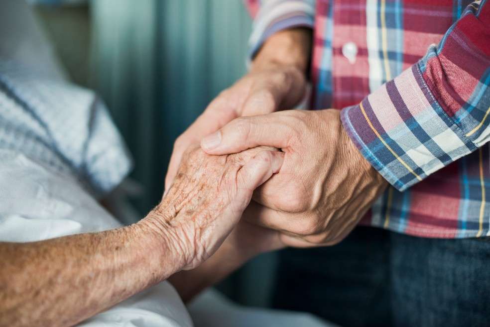 Unas manos jóvenes estrechan las manos de una señora de edad adulta.