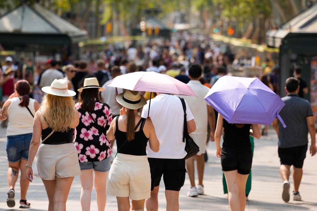 BARCELONA, 17/08/2025.- Un grupo de turistas se protege del sol con sombrillas este domingo en Barcelona. La larga ola de calor que afecta a España desde comienzos de agosto encara la recta final, pero hoy deja uno de los días más sofocantes, con temperaturas que a primera hora de la tarde marcaban 44,3 grados en Morón de la Frontera (Sevilla) y por encima de los 40 en muchas provincias. EFE/ Alejandro García