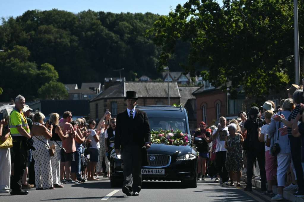 Mourners and fans line the streets to pay their respects as a hearse carrying the coffin of the late singer Bonnie Tyler is driven through her home town of Mumbles, southwest Wales, on August 15, 2026. Welsh singer Bonnie Tyler, best known for her powerful, haunting love song "Total Eclipse of the Heart" died in Portugal on July 8, 2026, aged 75. (Photo by JUSTIN TALLIS / AFP) / Correction - �The erroneous mention[s] appearing in the metadata of this photo by JUSTIN TALLIS has been modified in AFP systems in the following manner: [died in Portugal on July 8 2026,] instead of [died in Portugal on August 9, 2026,]. Please immediately remove the erroneous mention[s] from all your online services and delete it (them) from your servers. If you have been authorized by AFP to distribute it (them) to third parties, please ensure that the same actions are carried out by them. Failure to promptly comply with these instructions will entail liability on your part for any continued or post notification usage. Therefore we thank you very much for all your attention and prompt action. We are sorry for the inconvenience this notification may cause and remain at your disposal for any further information you may require.�