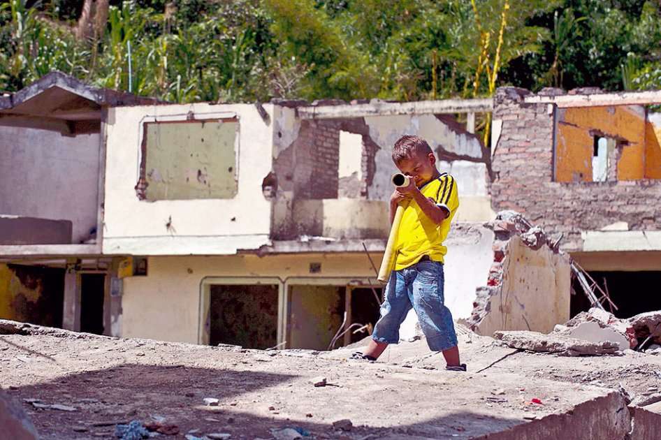 Un niño juega a la guerra en las ruinas de las casas contiguas a la estación de Policía de El Mango (Cauca). / AFP