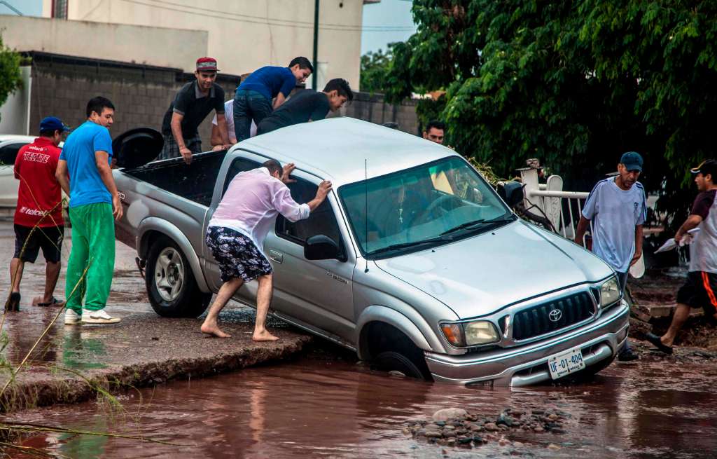 Las fuertes lluvias en Culiacán han causado muchos estragos. La gente intenta salvar sus vehículos y pertenencias.  / AFP