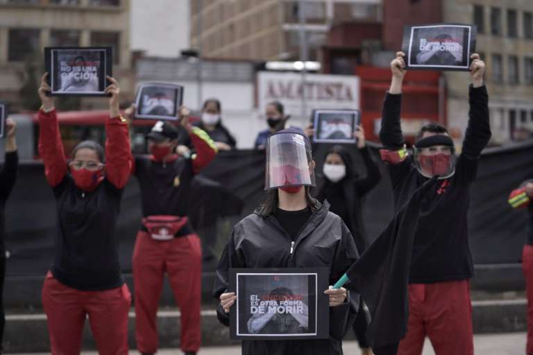 Personas con tapabocas sostienen carteles en los que se lee: el encierro es otra forma de morir
