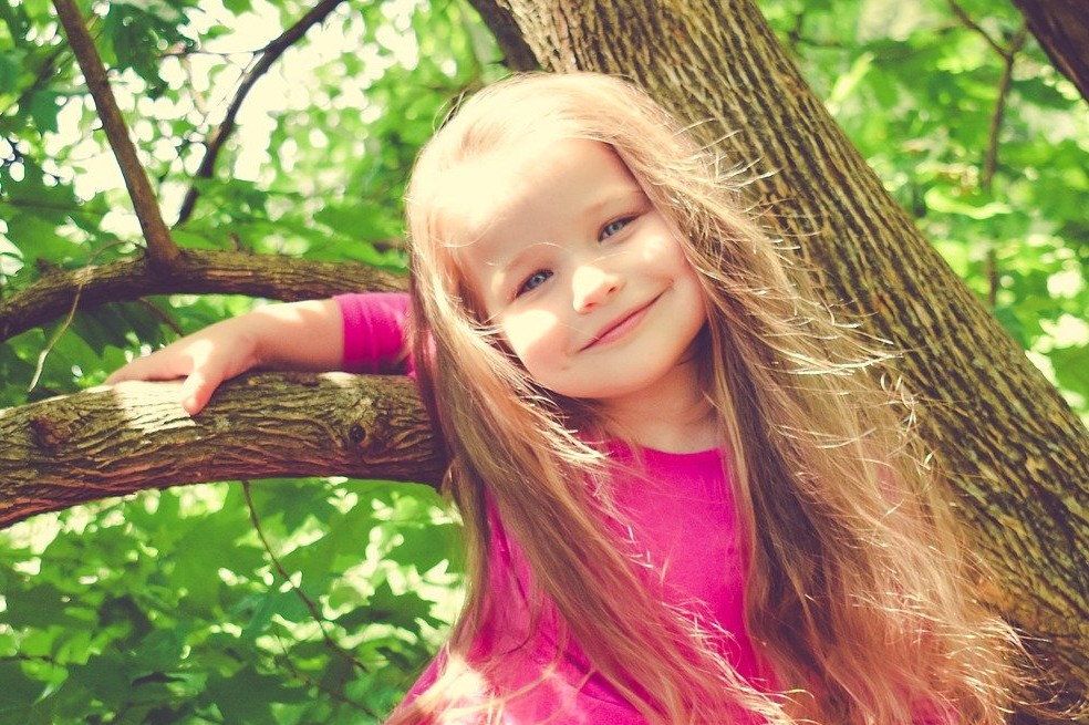 niña jugando en árbol
