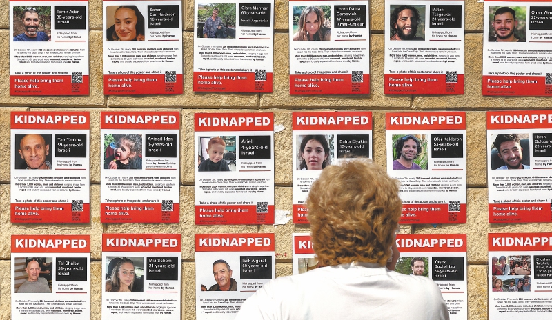Una mujer mira carteles que muestran fotografías de rehenes israelíes secuestrados por militantes palestinos desde el ataque del 7 de octubre, cerca del centro comercial Azrieli en Tel Aviv el 18 de octubre de 2023.