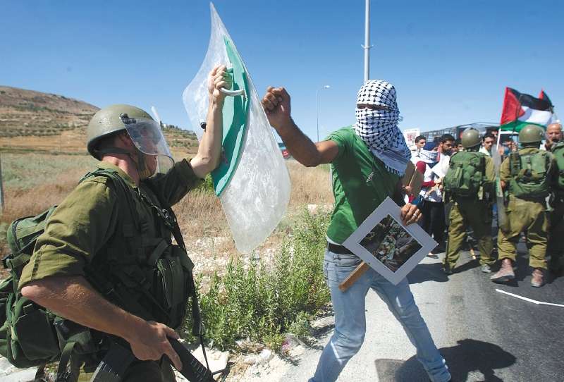 Los muertos en la guerra de Gaza superaron los 13.300. Aquí chocan un palestino y un soldado israelí.