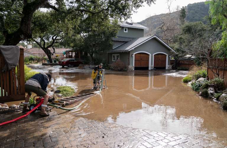 Carmel (United States), 11/01/2023.- Alan Crockett (C) helps his neighbor pump water off their home on Paso Honda after another wave of storms in Carmel Valley in Carmel, California, USA, 10 January 2023. California Governor Gavin Newsom proclaimed a state of emergency due to the winter storms. Many California counties are under flood warnings. (Estados Unidos) EFE/EPA/LIPO CHING