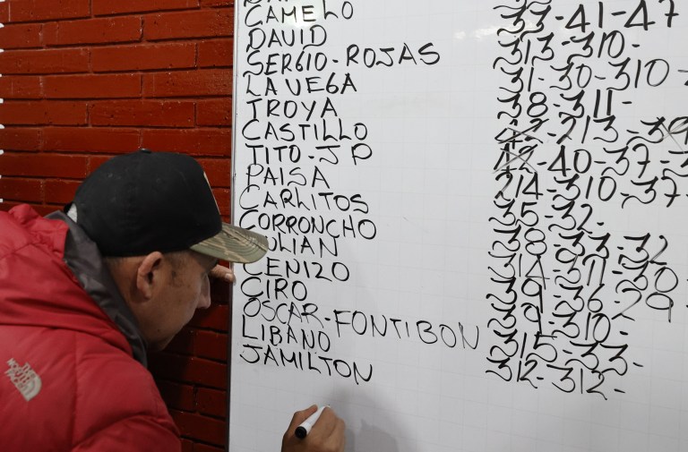 ACOMPAÑA CRÓNICA: COLOMBIA ANIMALES. BOG300. BOGOTÁ (COLOMBIA), 02/11/2022.- Un hombre escribe el peso de los gallos previo a una pelea, el 21 de octubre de 2022, en Bogotá (Colombia). En la pizarra de la entrada, con una caligrafía casi perfecta, los dueños de la gallera van anotando los rivales de la noche: los gallos no tienen nombre, no es relevante, pero sí lo es el peso y el tamaño para enfrentarlos en "condiciones justas" en un espectáculo que ha quedado atrapado en el tiempo en Colombia.EFE/ Mauricio Dueñas Castañeda