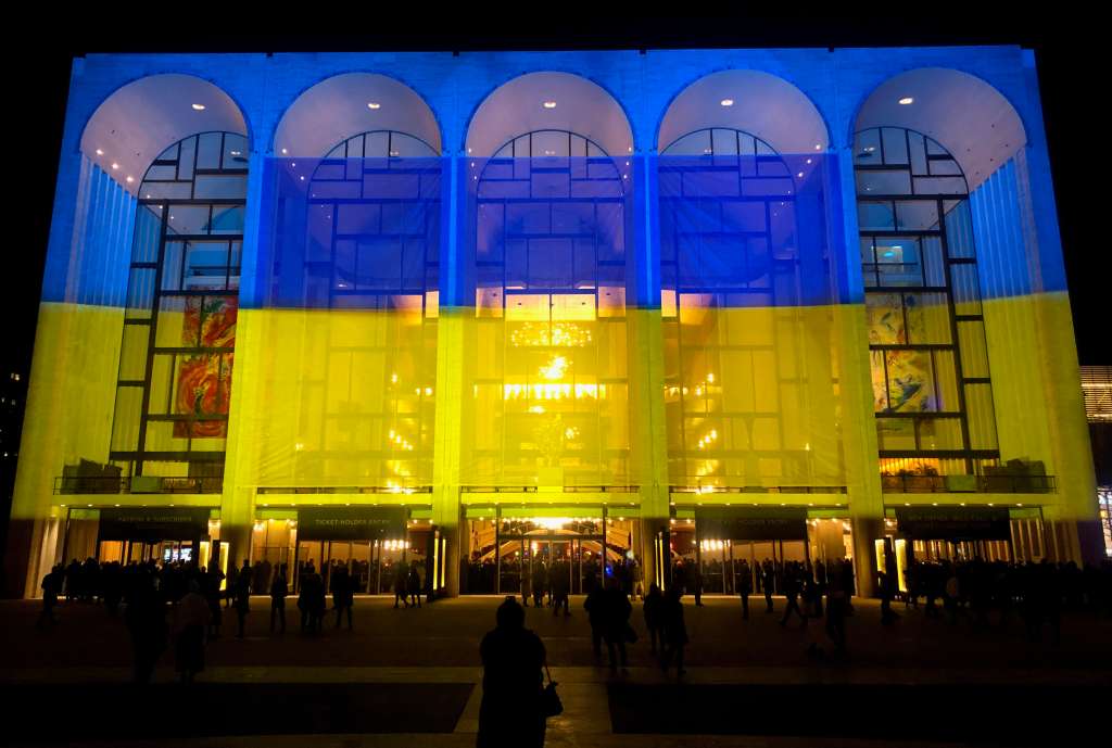 AME7631. NUEVA YORK (ESTADOS UNIDOS), 24/02/2023.- Fotografía de la fachada del Met Opera adornado con los colores de la bandera ucraniana, durante un concierto a favor de ese país ofrecido por la orquesta y coro de la Filarmónica de Nueva York, cuando se marca el primer aniversario de la invasión rusa, hoy, en Nueva York (EE.UU.). El Met Opera de Nueva York llenó este viernes los casi 4.000 asientos de su sala en el Lincoln Center en un "concierto de memoria y esperanza" para Ucrania celebrado exactamente cuando hoy se cumple un año de la guerra en el país europeo. El concierto comenzó con el himno de Ucrania, ante el cual todos los asistentes se pusieron en pie, y terminó también con la "Plegaria por Ucrania", de Valentin Silvestrov, una emotiva pieza cantada por el coro del Met Opera. EFE/ Javier Otazu