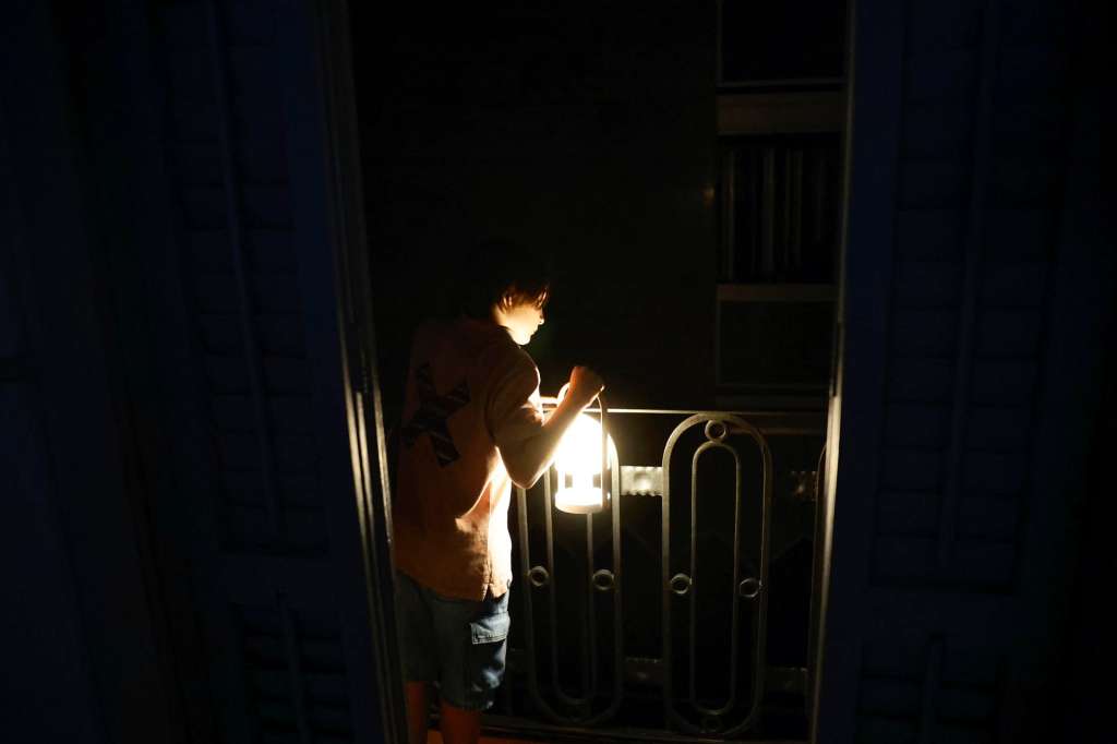 GRAFCAT7641. BARCELONA, 29/04/2025.- Un niño con una lampara mira desde el balcón la calle todavía a oscuras esta madrugada en el centro de Barcelona durante el corte de suministro eléctrico que afecta este lunes a España y que ha dejado sin servicio el metro y el tranvía de Barcelona y todas las líneas de ferrocarril, y sin red de teléfonos móviles ni internet. EFE/Alberto Estévez