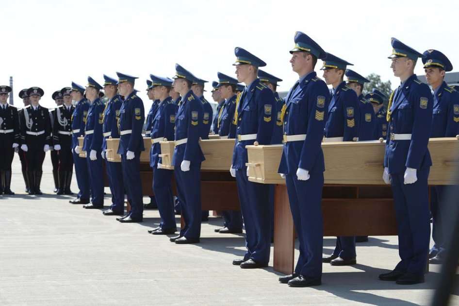 Unos soldados trasladan los ataúdes con los restos de las víctimas del vuelo MH17 de Malaysia Airlines a un avión militar durante una ceremonia en el aeropuerto de Járkov (Ucrania)