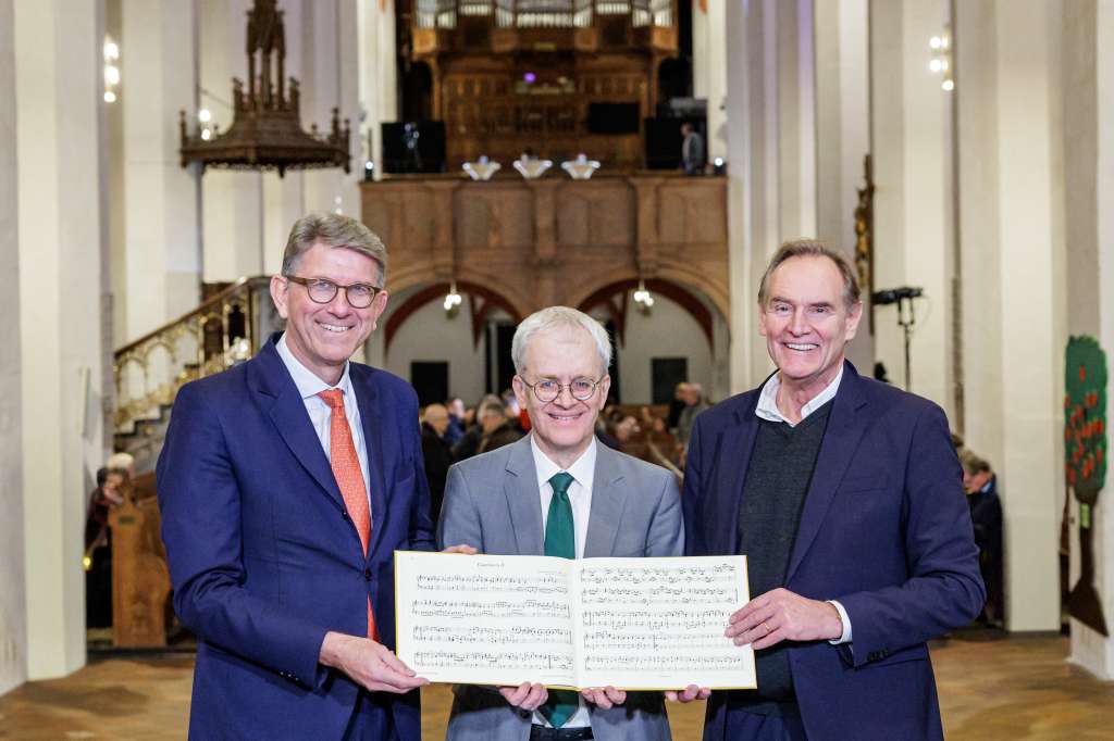 This handout picture released on November 17, 2025 by the Bach Archive Leipzig shows (L-R) German State Minister for Culture and Media Wolfram Weimer, director of the Bach Archive Peter Wollny and mayor of Leipzig Burkhard Jung holding a print of two long-lost organ pieces written by a teenage Johann Sebastian Bach during a presentation as part of the festival week celebrating the 75th anniversary of the Bach Archive Leipzig at the St. Thomas Church in Leipzig. Two long-lost organ pieces written by a teenage Johann Sebastian Bach were unveiled in Leipzig, on November 17, 2025 in a discovery described as a "great moment for the world of music". The two solo organ works, written while Bach was working as an organ teacher in the town of Arnstadt in Thuringia early in his career, first caught the attention of researchers over 30 years ago.They were also performed for the first time in 320 years at the St Thomas Church in Leipzig, where Bach is buried and served as a cantor for 27 years. (Photo by Jens Schlueter / BACH ARCHIVE / AFP) / RESTRICTED TO EDITORIAL USE - MANDATORY CREDIT "AFP PHOTO /JENS SCHLUETER/BACH ARCHIVE " - NO MARKETING - NO ADVERTISING CAMPAIGNS - DISTRIBUTED AS A SERVICE TO CLIENTS