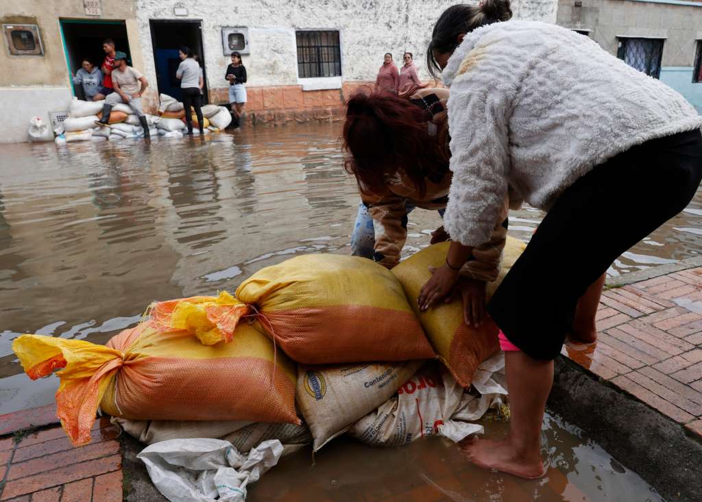 AME5640. FACATATIVÁ (COLOMBIA), 19/03/2026.- Personas usan sacos de arena para impedir que el agua entre a las casas debido a las inundaciones por fuertes lluvias este jueves, en Facatativá (Colombia). EFE/ Mauricio Dueñas Castañeda