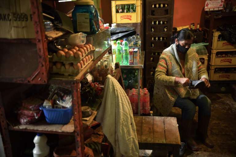 Una señora sentada en una tienda limpiando un zapato