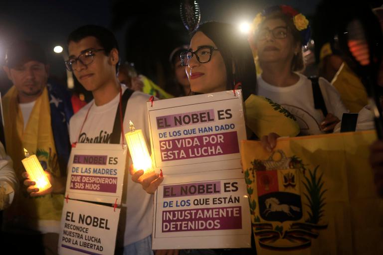 AME6424. CIUDAD DE PANAMÁ (PANAMÁ), 06/12/2025.- Personas sostienen carteles durante la marcha "por la paz y la libertad" en Venezuela este sábado, en Ciudad de Panamá (Panamá). Decenas de venezolanos se sumaron en Panamá a las marchas globales "por la paz y la libertad" en Venezuela convocadas el jueves por la líder opositora y exdiputada del país sudamericano María Corina Machado. EFE/ Bienvenido Velasco