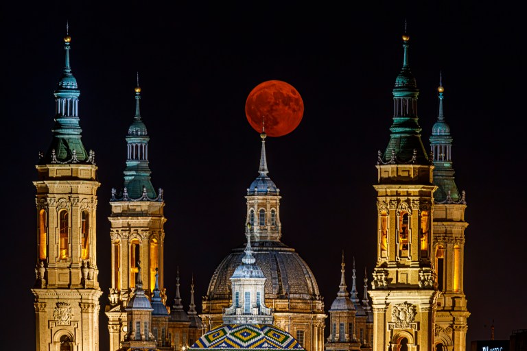 ZARAGOZA, 19/08/2024.- Fotografía de la luna llena de agosto este lunes, entre la calina y las torres de la Basílica de El Pilar de Zaragoza. EFE/ Javier Belver