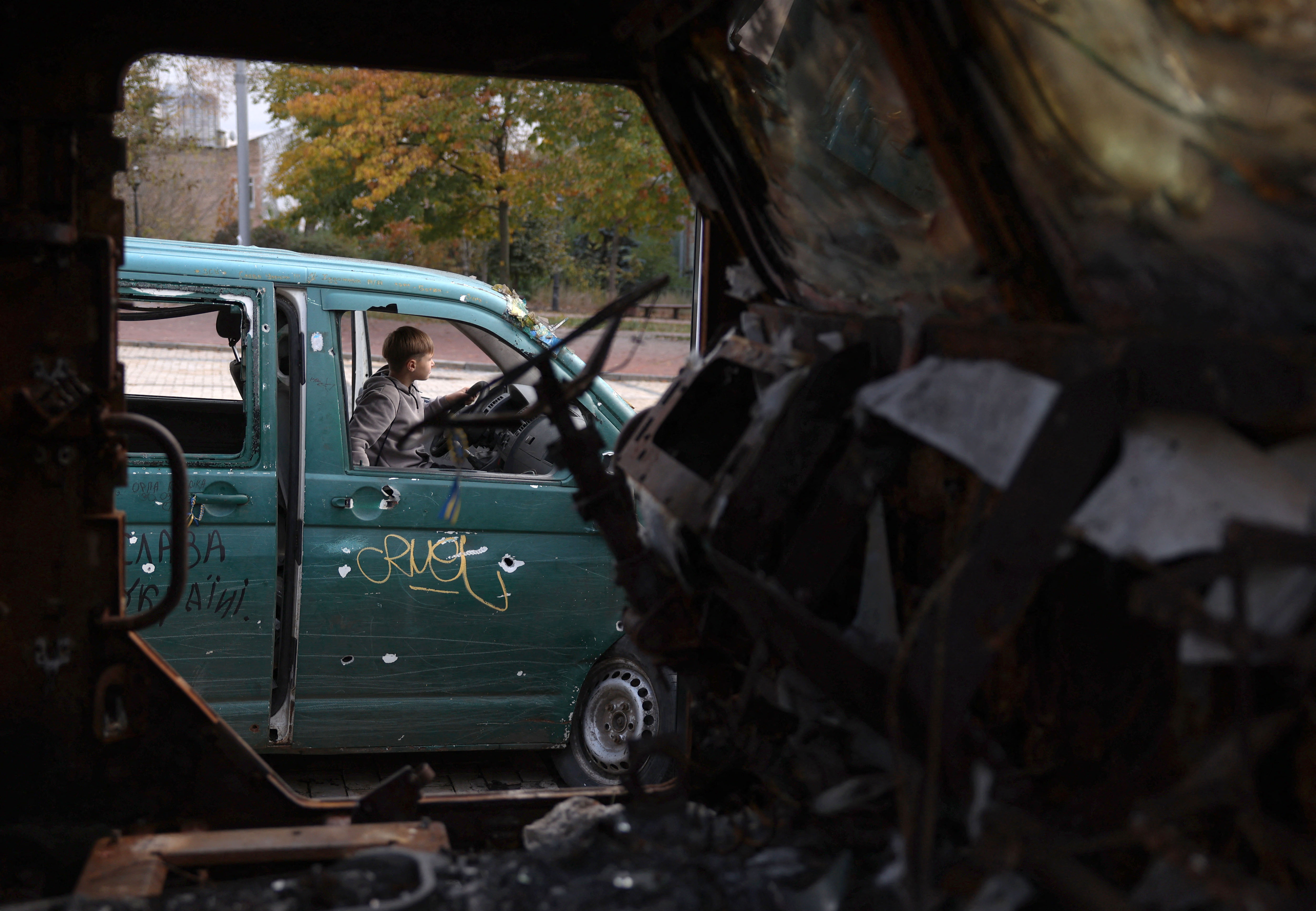 Un niño sentado en un automóvil destruido junto a vehículos militares rusos destruidos en exhibición frente al Monasterio de las Cúpulas Doradas de San Miguel en Kiev.