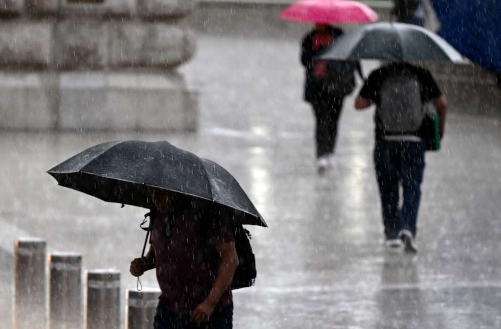 People shelter under umbrellas from the rain in Mexico City on August 13, 2025.