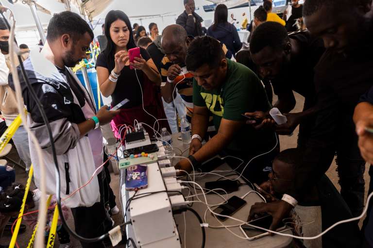 Somerton (United States), 12/05/2023.- Migrants pass calls and charge their phones at a migrant transition center after being released by Border Patrol, at the Regional Center for Border Health, in Somerton, Arizona, USA, 12 May 2023. A significant increase in the number of migrants crossing was expected as the Covid-era Title 42 policy, which allowed for a quick expulsion of illegal immigrants, expired at 23:59 ET on 11 May. (Estados Unidos) EFE/EPA/ETIENNE LAURENT