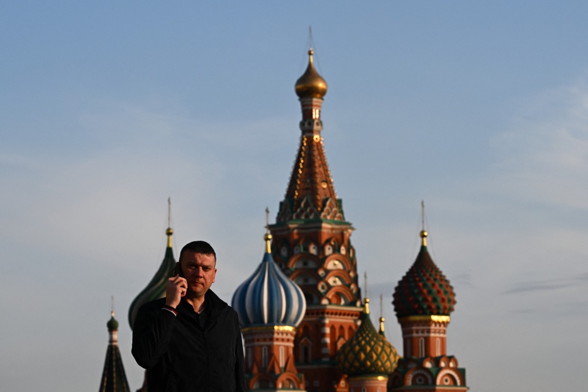 A man talks on a phone walking in front of St. Basil's cathedral on Red Square in central Moscow on March 17, 2026.