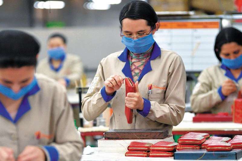Un grupo de trabajadoras laboran en una línea de confecciones de artículos de cuero.
