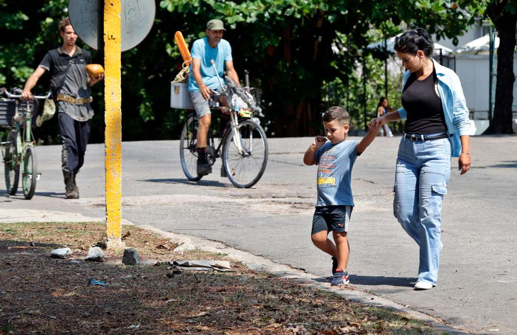 AME747. LA HABANA (CUBA), 10/05/2026.- Dania Leiva, de 35 años camina con su hijo este miércoles, en La Habana (Cuba). Dos madres cubanas viven a solo cinco kilómetros de distancia en La Habana, pero sus realidades son diametralmente opuestas: de un hogar con ciertas condiciones pese a la crisis a otro donde conviven la crianza de cerdos y la vida doméstica en pocos metros cuadrados. EFE/ Ernesto Mastrascusa