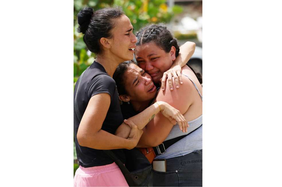 Gabriela Rojas es consolada frente a su casa dañada, donde dos de sus hijos fallecieron, en La Guaira.