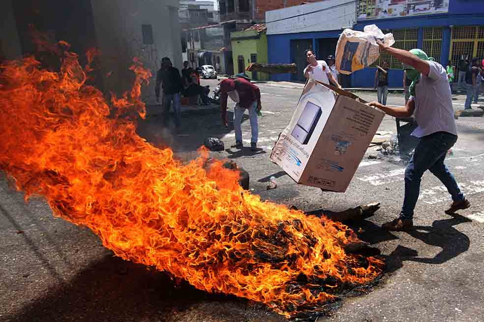Un grupo de jóvenes bloquean una vía de San Cristóbal con fuego, después del asesinato del menor Kluivert Roa. / AFP