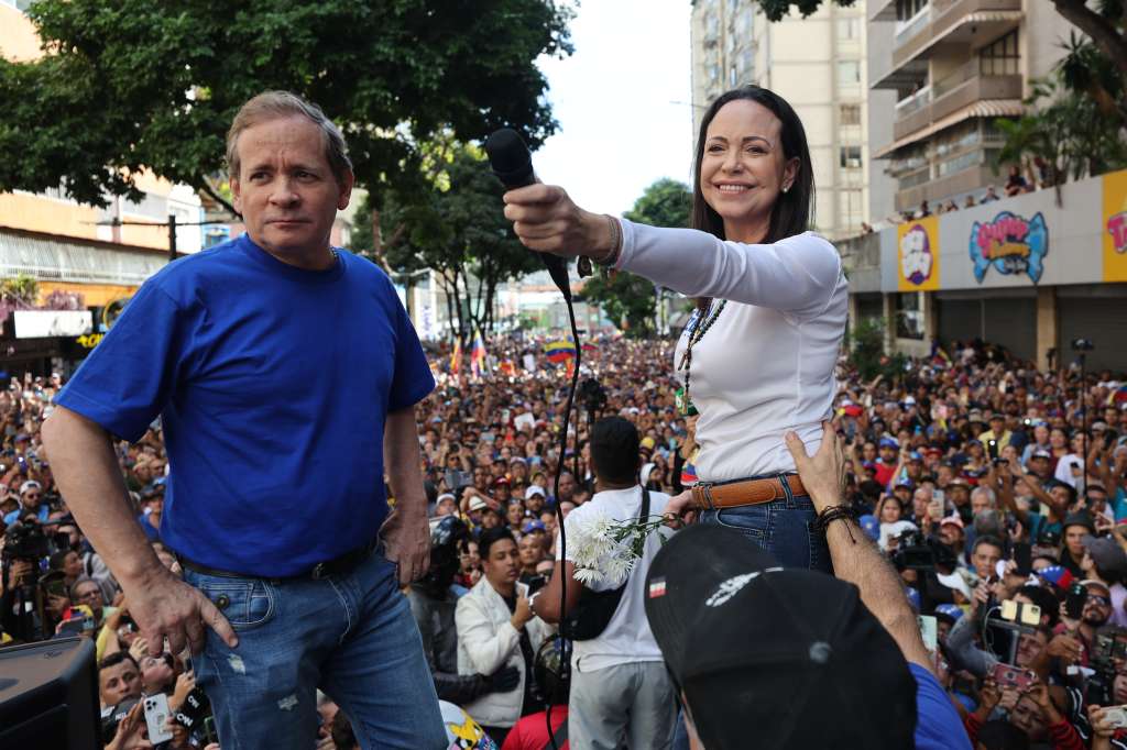AME9799. CARACAS (VENEZUELA), 09/01/2025.- La líder antichavista María Corina Machado (d) saluda a sus seguidores junto al exdiputado venezolano Juan Pablo Guanipa este jueves, en una manifestación en Caracas (Venezuela). Machado anunció, a un día de la toma de posesión presidencial, el comienzo de una "nueva fase" del proceso para "la libertad de Venezuela", y pidió a los ciudadanos estar atentos a las señales sobre los próximos pasos. EFE/ Miguel Gutiérrez