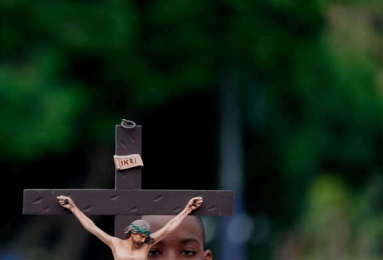 -FOTODELDÍA- AME3528. CALI (COLOMBIA), 29/03/2024.- Un niño sostiene una imagen de Jesucristo crucificado durante la procesión del Santo Viacrucis este Viernes Santo, como parte de las celebraciones de la Semana Santa, en Cali (Colombia). EFE/Ernesto Guzmán