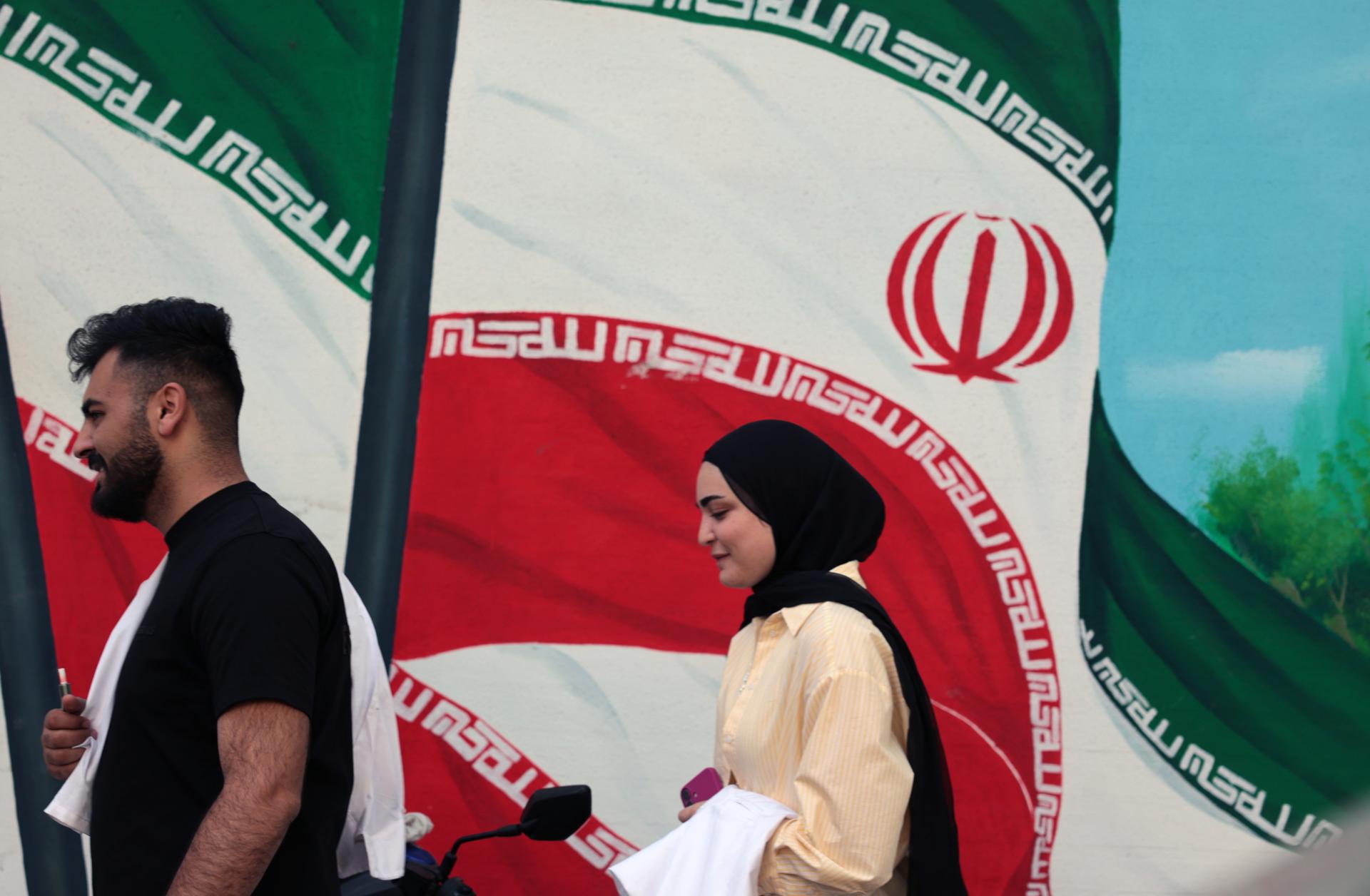 TEHRAN (Iran (Islamic Republic Of)), 11/05/2025.- People walk next to a mural with the Iranian national flag in Tehran, Iran, 11 May 2025. Iran and the US hold their fourth round of nuclear talks in Muscat on the same day. (Teherán) EFE/EPA/ABEDIN TAHERKENAREH