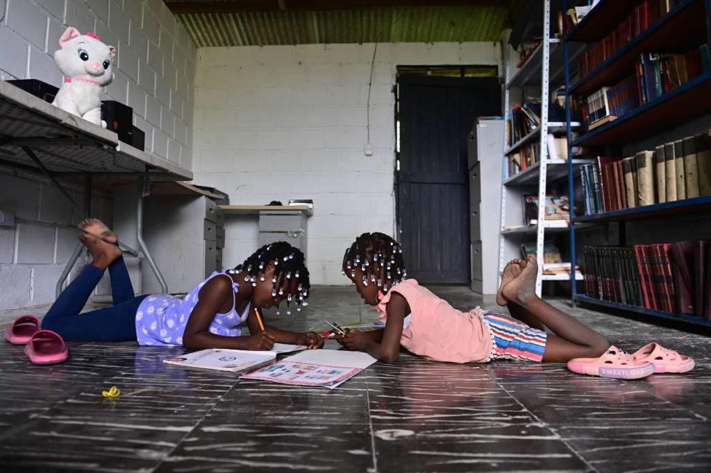 Dos niñas leen en la biblioteca que ha venido construyendo la Asociación de Jóvenes Emprendedores de Paz.