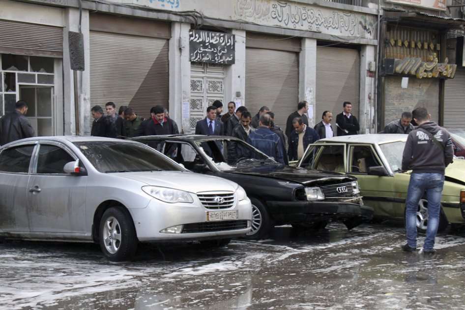 Sirios observan los destrozos a unas cuadras de donde estalló una bomba en Damasco/ EFE