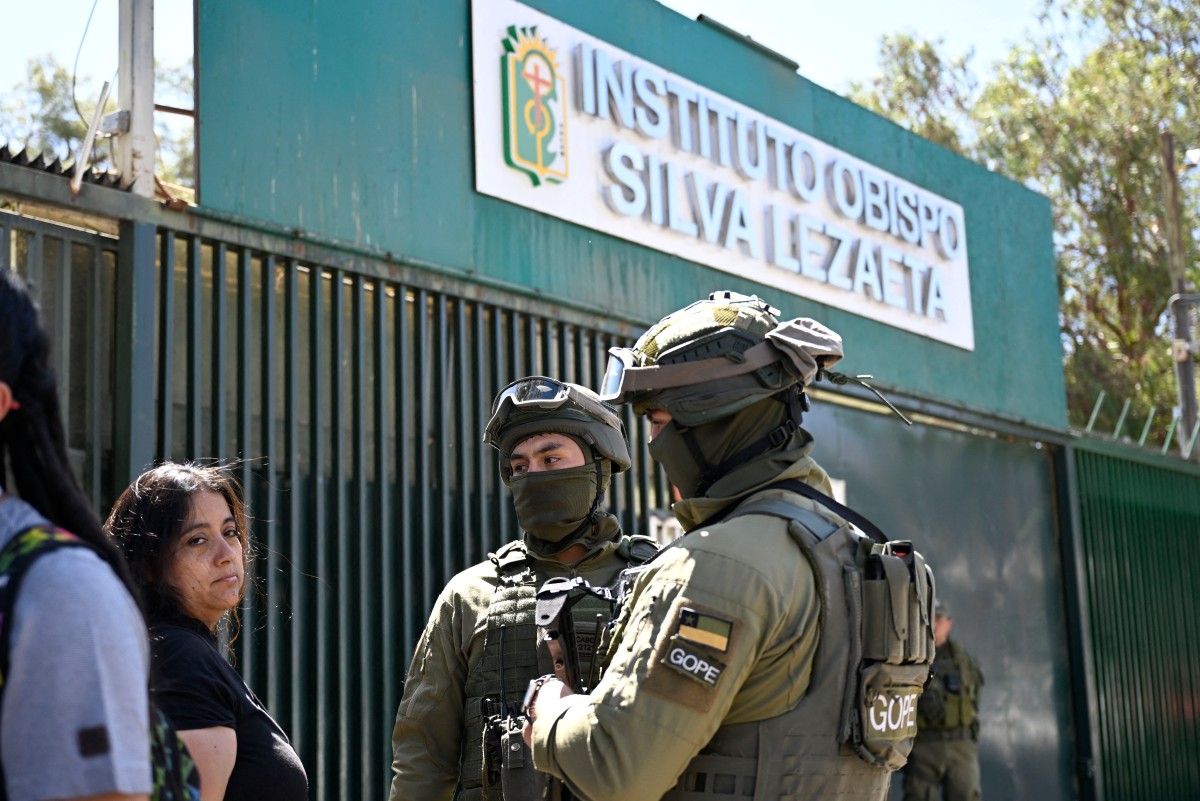 Family members wait outside the Instituto Obispo Silva Lezaeta school as police stand guard at the entrance after an armed student attacked classmates and teachers in Calama, northern Chile, on March 27, 2026.